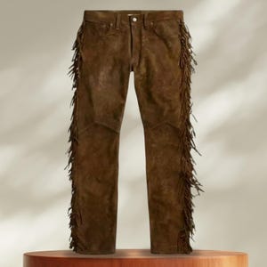 May include: Brown suede pants with fringe detailing along the sides.