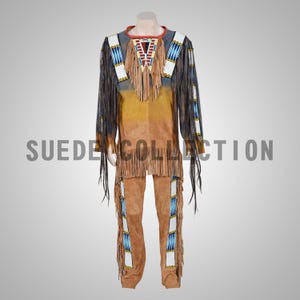 Pode incluir: Um traje de camurça com uma camisa de mangas compridas e calças. A camisa tem gola vermelha, pala com contas e franjas. As calças têm detalhes de contas e franjas. O texto "SUEDE COLLECTION" é visível.