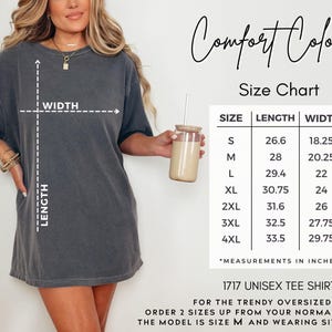 Pode incluir: Uma camiseta unissex cinza carv&atilde;o com uma tabela de tamanhos e o texto "Comfort Colors". A tabela de tamanhos mostra medidas em polegadas para os tamanhos S a 4XL. O texto abaixo diz "1717 Unisex Tee Shirt."