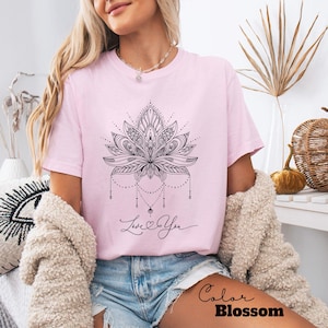 Pode incluir: Camiseta rosa claro com um design detalhado de flor de l&oacute;tus preta. A camiseta inclui o texto manuscrito "Love You" e o nome da marca "Color Blossom". A camiseta &eacute; feita de um material macio.