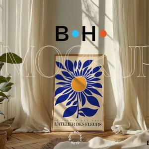 Puede incluir: Una impresi&oacute;n enmarcada de una flor estilizada azul y blanca con un centro amarillo. La impresi&oacute;n se titula "L'ATELIER DES FLEURS" y se coloca contra una pared blanca con cortinas blancas.