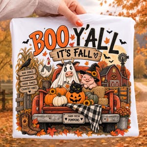 Könnte beinhalten: Ein weißes T-Shirt mit einer Grafik eines roten Pick-ups voller Kürbisse, einer Kuh im Geisterkostüm, einem Schwein mit Hexenhut und einer schwarzen Katze. Der Text lautet BOO Y'ALL IT'S FALL, HAY RIDES, PUMPKINS, GOOD TIMES, COUNTRY VIBES und FARM FRESH PUMPKINS.