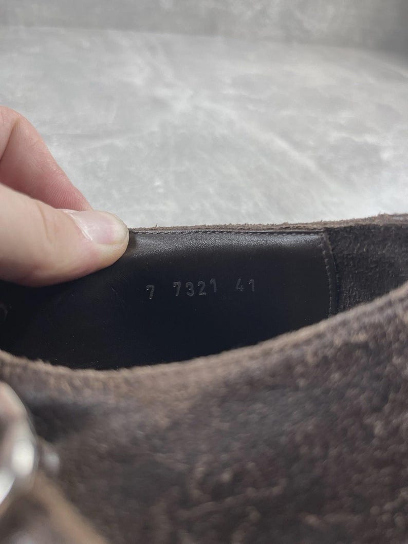 May include: Close-up of a brown suede shoe. The interior shows the numbers "7 7321 41" stamped in white. The shoe has a textured surface and a dark brown leather interior.