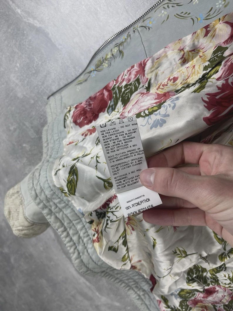 Peut inclure: Veste bleu clair avec un motif floral sur l'ext&eacute;rieur et une doublure &agrave; imprim&eacute; floral vif. La veste a une fermeture &eacute;clair et une &eacute;tiquette avec des instructions d'entretien et la composition du tissu : 100% Python Reticulatus.
