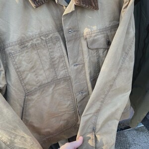Puede incluir: Una chaqueta utilitaria de color tostado con cuello de pana marr&oacute;n, cierre frontal de botones y dos grandes bolsillos de parche. La prenda incluye un bolsillo en el pecho con solapa abotonada y mangas largas con pu&ntilde;os ajustables, con forro acolchado.