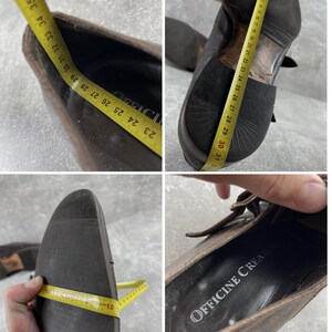 May include: Brown leather shoes with a buckle closure. The shoes are being measured with a yellow measuring tape. The sole of the shoe is dark brown. The interior of the shoe has the text "OFFICINE CREATE".