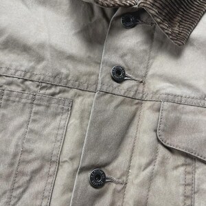 Puede incluir: Una chaqueta de color tostado con cuello de pana marr&oacute;n y forro interior acolchado. La parte delantera incluye una tapeta con botones negros grabados con el texto C.C. FILSON CO. SEATTLE, junto con dos grandes bolsillos frontales de parche.
