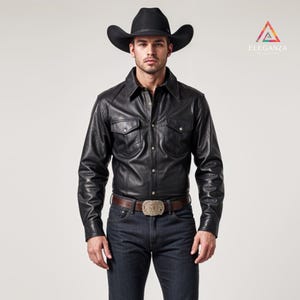 May include: A black leather shirt with two chest pockets and a button-down front. The shirt is paired with dark wash denim jeans and a brown leather belt with a decorative buckle. A black cowboy hat completes the look.