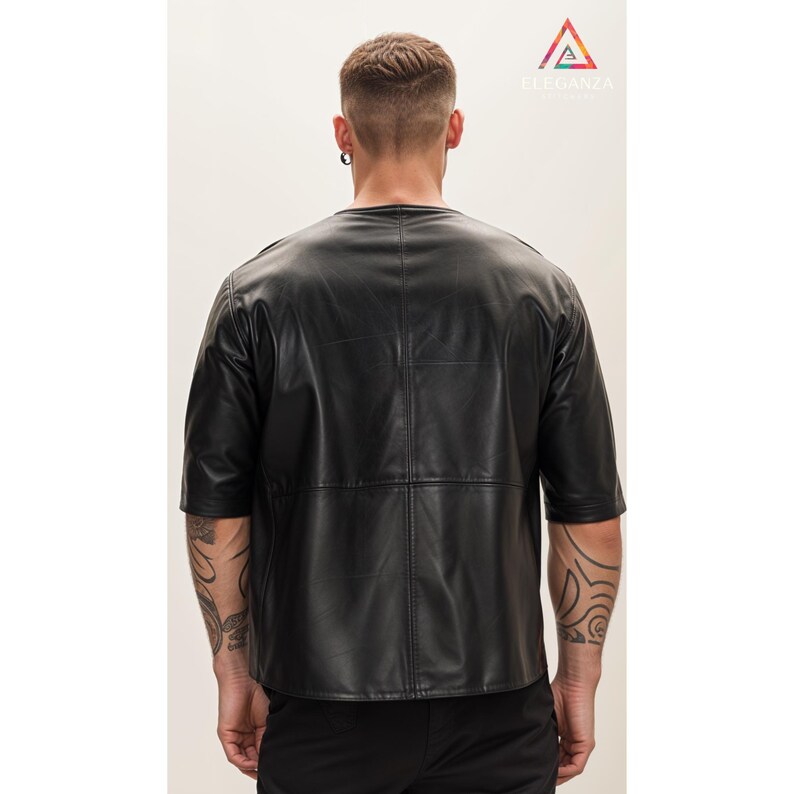 May include: A black leather short-sleeved shirt with a round neckline. The shirt has a panel design and is made of a smooth, textured material.