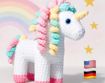 Puede incluir: Un peluche de unicornio tejido a ganchillo en color blanco con una crin y cola en espiral de hilo en tonos pastel rosa, amarillo y verde azulado. El unicornio tiene un cuerno amarillo, ojos azul brillante y pezuñas rosas. Incluye un arcoíris y estrellas amarillas.
