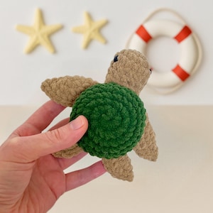 May include: A green and brown crocheted turtle toy. The turtle has a green shell and brown limbs and head.