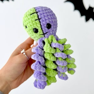 Puede incluir: Un pulpo de peluche hecho de hilo suave y difuso en secciones alternas de color verde lima y morado. La cabeza presenta una costura vertical negra en el centro y dos ojos pequeños, redondos y de plástico negro. Tiene varios tentáculos rizados.