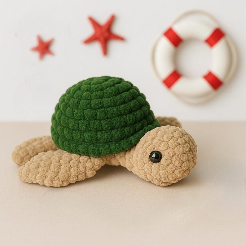May include: A crocheted stuffed turtle toy with a green shell and beige body. The turtle has black eyes and is lying on a beige surface.