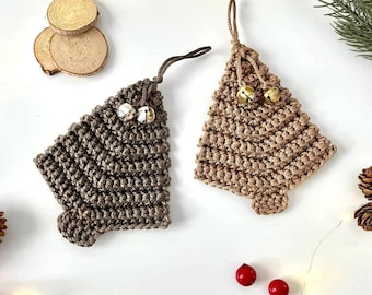 Op de afbeelding: Twee handgemaakte kerstboomversieringen. Eén is donkerbruin, de andere is bruin. Beide zijn gehaakt met een belletje aan de bovenkant. De versieringen liggen op een witte ondergrond met decoratieve elementen.