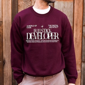 May include: A maroon crewneck sweatshirt featuring white text that reads A WORLD OF CODE, THE DIGITAL ARCHITECT, FULLSTACK DEVELOPER, and BRIDGING FRONT AND BACK—BUILDING SEAMLESS EXPERIENCES, SOLVING COMPLEX PROBLEMS, AND MAKING THE WEB WORK.