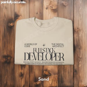 A white t-shirt with text printed on it, laid out on a wooden surface.