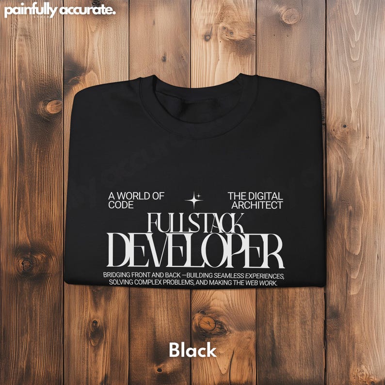 A black t-shirt with white text printed on it, laid out on a wooden surface.