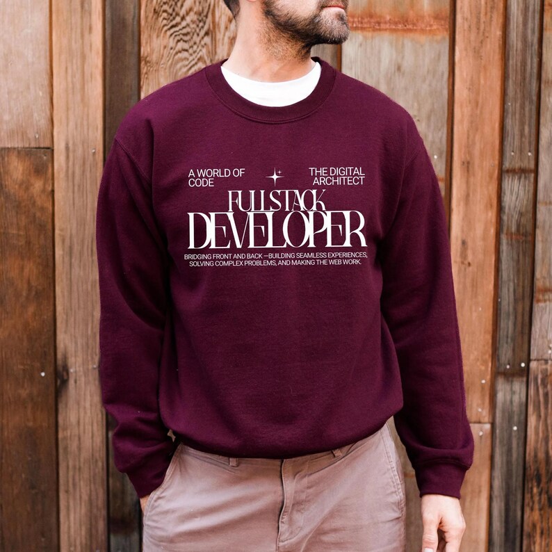 A man wearing a burgundy sweatshirt with white text on it, standing in front of a wooden wall.