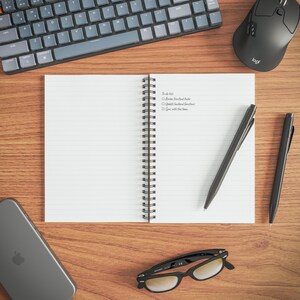 a wooden desk with various office supplies and a notebook with a list of tasks written on it.