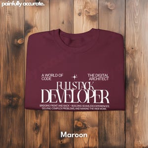 A maroon t-shirt with white text is displayed on a wooden background.
