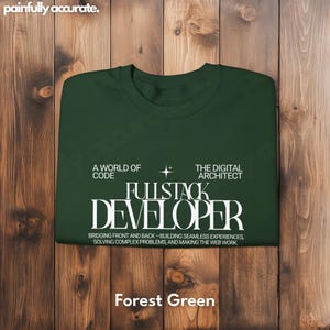 A green t-shirt with white text is displayed on a wooden background.