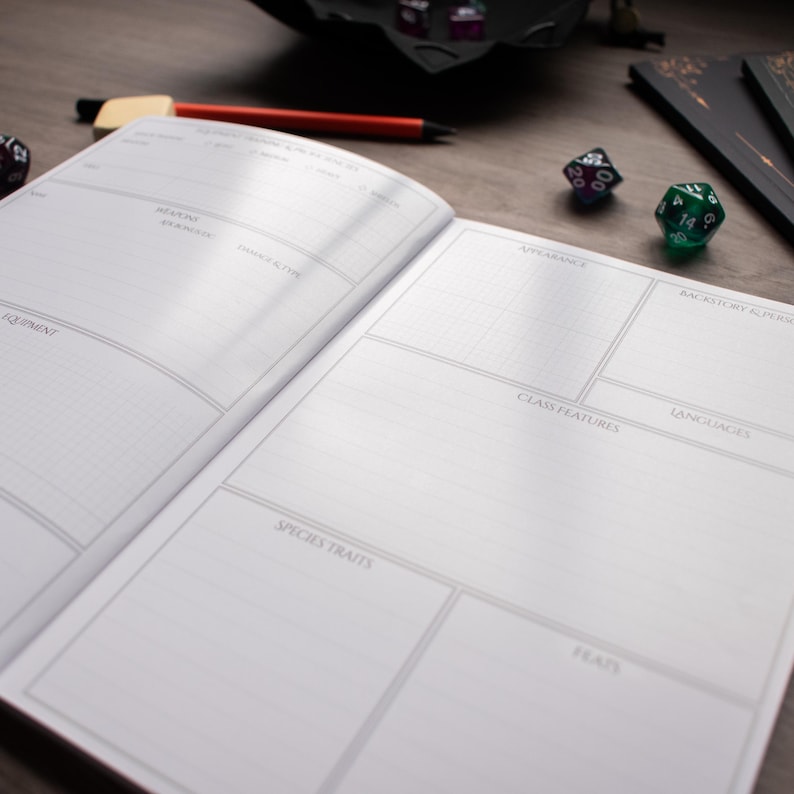 An open notebook with blank pages, a pen, and two dice on a wooden surface.