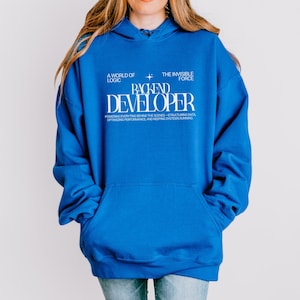 May include: A royal blue hoodie with a front pocket and a drawstring hood. The front of the hoodie features white text that reads "A WORLD OF LOGIC", "THE INVISIBLE FORCE", and "BACKEND DEVELOPER". Below the text is the phrase "POWERING EVERYTHING BEHIND THE SCENES - STRUCTURING DATA, OPTIMIZING PERFORMANCE, AND KEEPING SYSTEMS RUNNING."
