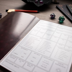 an open notebook with a detailed character sheet or inventory list, along with a pen and a pair of dice on a wooden surface.