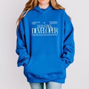 Könnte beinhalten: Ein leuchtend blauer Kapuzenpullover mit weißem Textaufdruck, der A WORLD OF CODE, THE DIGITAL ARCHITECT, FULLSTACK DEVELOPER sowie BRIDGING FRONT AND BACK—BUILDING SEAMLESS EXPERIENCES, SOLVING COMPLEX PROBLEMS, AND MAKING THE WEB WORK lautet.