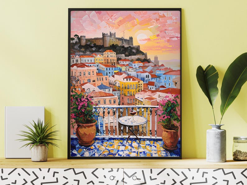 K&ouml;nnte beinhalten: Ein gerahmtes &Ouml;lgem&auml;lde, das eine mediterrane Stadtlandschaft bei Sonnenuntergang zeigt. Die Szene umfasst einen Balkon mit einem kleinen runden Tisch, einem Weinglas und zwei gro&szlig;en Terrakottat&ouml;pfen mit rosa Blumen, die &uuml;ber die H&auml;user blicken.