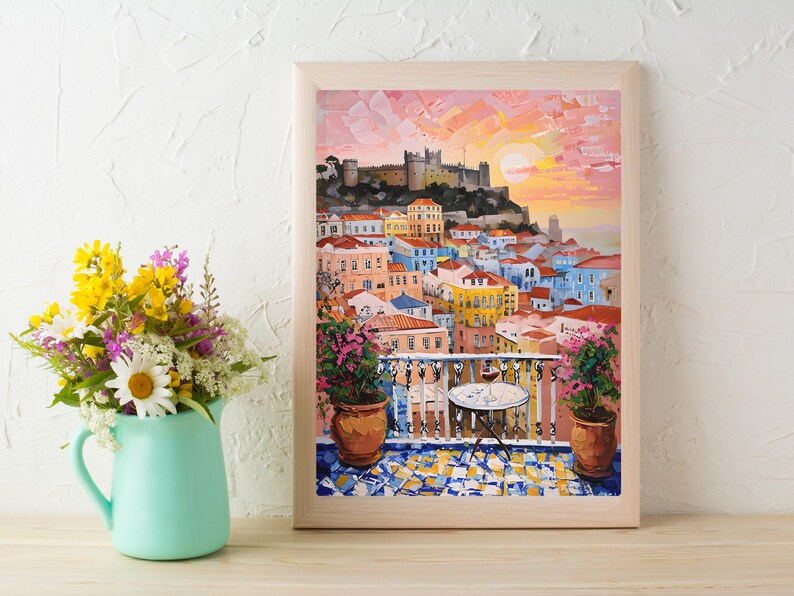 K&ouml;nnte beinhalten: Ein gerahmtes &Ouml;lgem&auml;lde, das einen mediterranen Balkon mit Blick auf eine Stadt mit bunten Geb&auml;uden und eine Burg auf einem H&uuml;gel bei Sonnenuntergang zeigt. Ein kleiner runder Tisch mit einem Weinglas steht auf dem gefliesten Balkon.