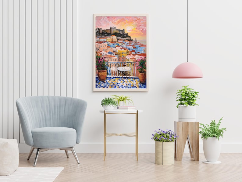 K&ouml;nnte beinhalten: Ein gerahmter Wandkunstdruck, der ein lebhaftes mediterranes Stadtbild bei Sonnenuntergang zeigt, mit einem Balkon, einem kleinen Tisch, Topfpflanzen und einem gefliesten Boden mit Blick auf bunte Geb&auml;ude und eine Burg auf einem H&uuml;gel.