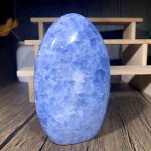 以下が含まれることがあります： 卵の形に彫刻された薄い青色のセレスティン結晶。結晶は滑らかで磨かれた表面を持ち、全体に曇った白い模様があります。