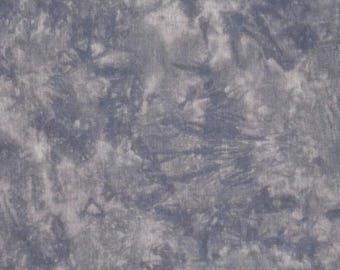 May include: A close-up of a fabric with a tie-dye pattern in shades of gray and blue. The fabric has a textured appearance with a mottled design, creating a cloudy or marbled effect. The material appears to be a woven textile.