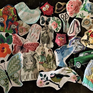 May include: A collection of fabric patches with various designs, including butterflies, owls, flowers, and a green car. The patches feature a mix of colors and patterns, creating a whimsical and artistic display. Some patches have text, and others depict animals.