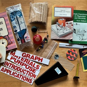 May include: A collection of educational science materials, including books titled "Physics Experiments for Children" and "Simple Experiments on Magnetism and Electricity." Also includes a model ear, butterflies, and various experiment supplies.