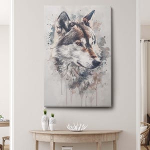 May include: A canvas print featuring a watercolor-style portrait of a wolf. The wolf's head is depicted in shades of brown, gray, and white, with a splash of color around the edges. The artwork is mounted on a rectangular canvas.