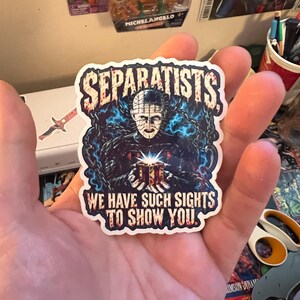 May include: A die-cut vinyl sticker featuring a central illustration of Pinhead from Hellraiser holding a glowing puzzle box, surrounded by blue chains. The text SEPARATISTS appears at the top and WE HAVE SUCH SIGHTS TO SHOW YOU at the bottom.