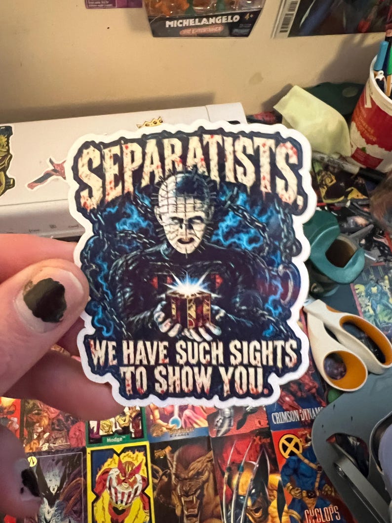 May include: A die-cut sticker featuring a pale, pin-headed figure in a black outfit surrounded by blue chains, holding a glowing puzzle box. The text SEPARATISTS appears at the top, and WE HAVE SUCH SIGHTS TO SHOW YOU is printed at the bottom.