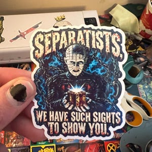 May include: A die-cut sticker featuring a horror character with a pin-covered head, surrounded by blue energy and chains, holding a glowing puzzle box. The text SEPARATISTS is at the top, and WE HAVE SUCH SIGHTS TO SHOW YOU is at the bottom in red.