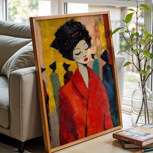 Può includere: Una stampa artistica incorniciata raffigurante una donna con un cappotto rosso e un copricapo nero. Il dipinto ha uno sfondo giallo e arancione con figure sullo sfondo. L'opera d'arte è appoggiata a un divano beige vicino a una finestra.