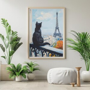 Può includere: Stampa artistica incorniciata di un gatto nero seduto su un balcone, con la Torre Eiffel sullo sfondo. Il dipinto presenta un cielo azzurro chiaro, nuvole ed edifici parigini. L'opera è in una cornice di legno.