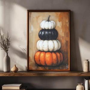 Può includere: Dipinto incorniciato raffigurante una pila di zucche arancioni, bianche e nere. Le zucche sono disposte verticalmente su uno sfondo caldo e strutturato. L'opera d'arte è esposta su una mensola di legno.