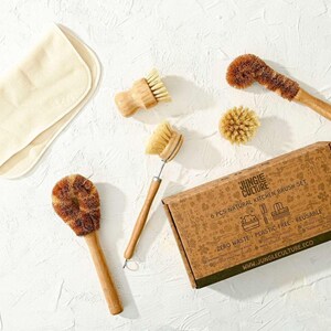May include: A set of six natural kitchen brushes in a cardboard box. The brushes are made of bamboo and sisal and are designed for cleaning dishes, fruits, and vegetables. The box is brown and has a white label with the text "Jungle Culture 6 PCS NATURAL KITCHEN BRUSH SET ZERO WASTE | PLASTIC FREE | REUSABLE WWW.JUNGLECULTURE.ECO".