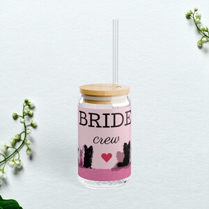 May include: A clear glass can with a pink background and a bamboo lid. The can has a black and white graphic of dogs and the text "BRIDE crew" with a pink heart.
