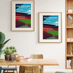 K&ouml;nnte beinhalten: Zwei gerahmte Kunstdrucke des Old Trafford-Stadions, Manchester United, in einer stilisierten Illustration. Die Drucke zeigen das &Auml;u&szlig;ere des Stadions mit roten Sitzen, einem gr&uuml;nen Spielfeld und blauem Himmel. Der Text lautet "OLD TRAFFORD" und "MANCHESTER UNITED".