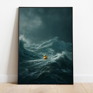May include: A framed art print depicts a yellow rubber duck floating in a turbulent ocean. The dark, stormy sky contrasts with the bright yellow of the duck, creating a striking visual. The artwork is displayed on a wooden floor against a white wall.