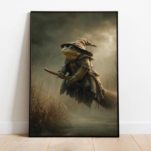 May include: A framed print depicting a frog dressed as a witch, riding a broomstick. The frog is wearing a pointed hat and tattered clothes, set against a misty background of tall grass and a dark, overcast sky. The artwork evokes a fantasy theme.