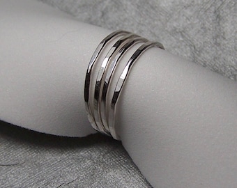 May include: Five silver hammered stacking rings. The rings are thin and delicate, and they are stacked on top of each other.