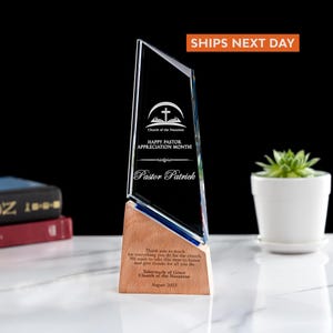 May include: A clear glass and wood pastor appreciation award. The glass portion has the text "HAPPY PASTOR APPRECIATION MONTH!" and "Pastor Patrick". The wooden base has a message from the Tabernacle of Grace Church of the Nazarene, dated August 2025.